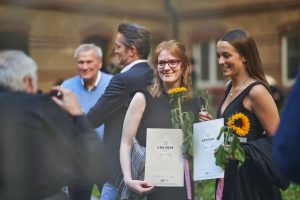 Zwei Frauen mit Bachelorurkunden und Blumen nach Abschluss an der Uni – Eventfotograf Hamburg