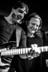 Gitarrist und Saenger lachen bei einem Liveauftritt – Musikfotograf Hamburg