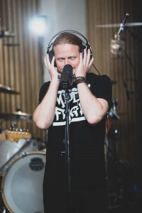 Saenger der Band Salty Saints im Tonstudio vor dem Mikrofon – Musikfotograf Hamburg