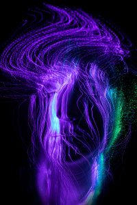 Experimentelles Langzeitportrait mit violetten Lichtspuren einer Glasfaserlampe auf dem Gesicht – People Fotograf Hamburg