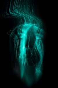 Experimentelles Langzeitportrait mit tuerkisen Lichtspuren einer Glasfaserlampe auf dem Gesicht – People Fotograf Hamburg