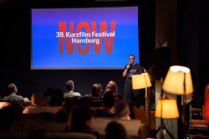 Mann und Publikum vor Leinwand beim Hamburg Animation Club – Eventfotograf Hamburg