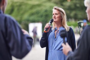 Frau mit Mikrofon leitet einen Rundgang durch eine Fotoausstellung – Eventfotograf Hamburg