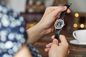 Frau hält eine Hentschel Uhr in den Händen und sitzt im Cafe – Produktfotograf Hamburg