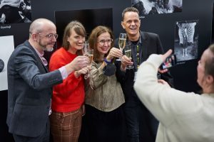Froehliche Gruppe mit Sektglaesern bei einer Fotoausstellung – Eventfotograf Hamburg