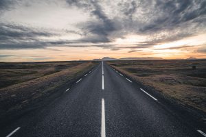 Lange Straße durch ebene Landschaft in Island mit Sonnenuntergang – Landschaftsfotograf Hamburg