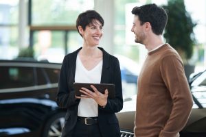 Frau mit Tablet fuehrt ein Kundengespraech mit einem Autokaeufer – People Fotograf Hamburg
