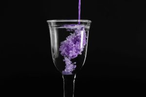 Dunkle Studiofotografie eines Weinglases in das violette Farbe gefüllt wird – Produktfotograf Hamburg