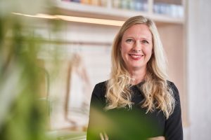 Blonde Fru laechelt vor ihrer Kueche