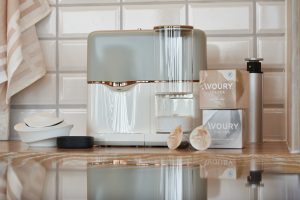 Eine grau weiße Teemaschine steht auf einer Holzplatte vor weißen Fliesen