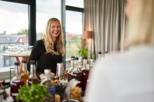 Blonde Frau steht an einer Bar und lacht